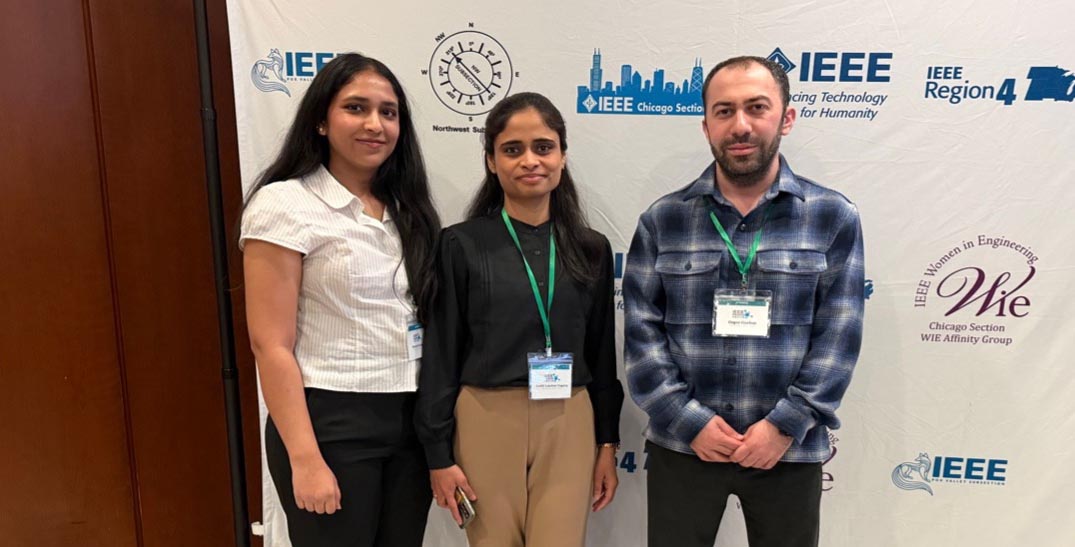 Sheetal, Jyothi, and Ozgur stand side-by-side for a photo in front of a step-and-repeat of IEEE (Institute of Electrical and Electronics Engineers) and 'Women in Engineering' (WIE) logos.