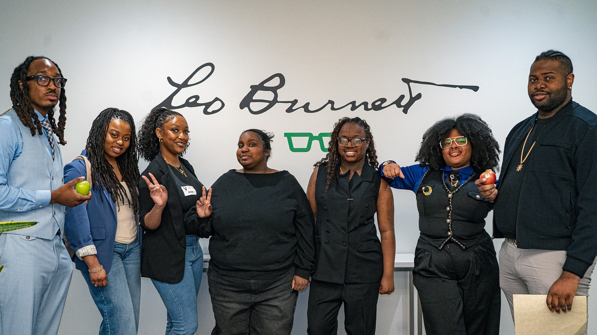 A group of seven people stands in a row posing together in front of a white wall featuring the Leo Burnett signature logo.