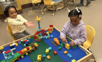 Children sitting at a table, playing with legos
