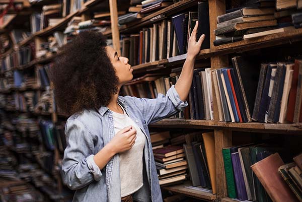 Student Examing Books in Library 