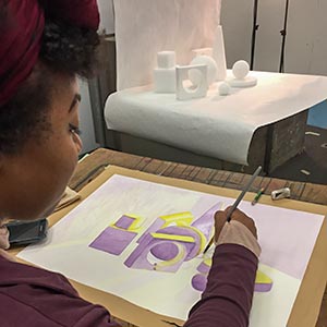 An over-the-shoulder photo of a student sketching with a pencil